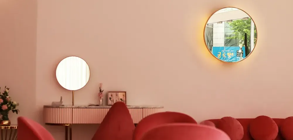 two round gold mirrors in a pink barbiecore style room