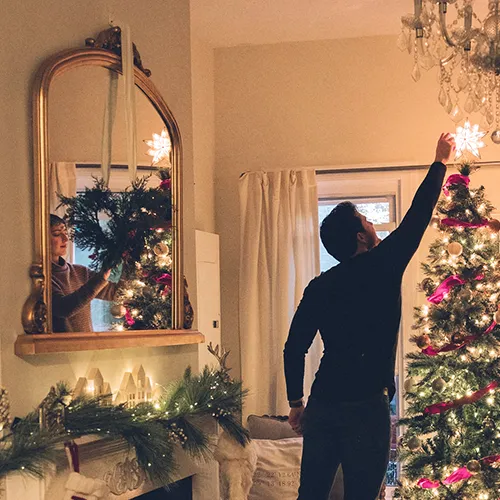 people decorating for Christmas with mirror over fireplace