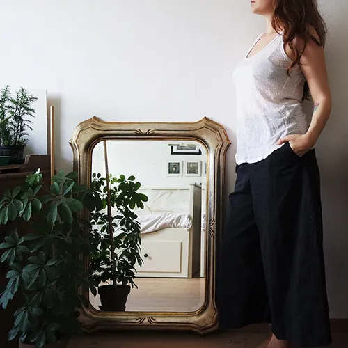 woman stood near framed mirror reflecting bed