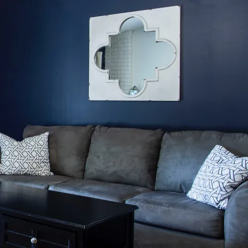 grey sofa in living room with white shaped mirror on wall