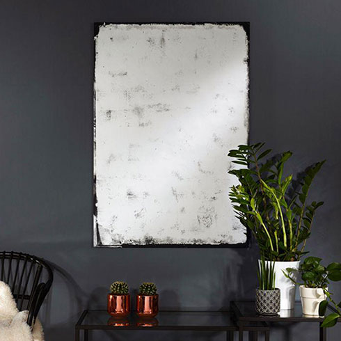 large distressed wall mirror rectangular hanging on dark grey wall over side table