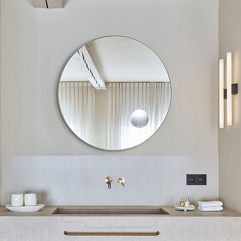 Round bathroom mirror with circular magnified section hanging above contemporary sink