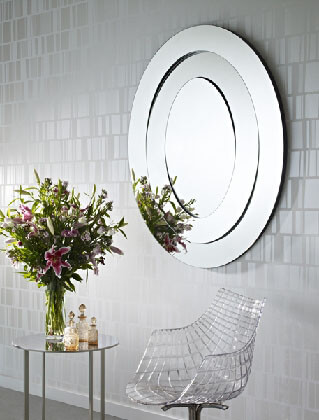 oval multi facet frameless mirror on wall near chair and table with perfume bottles
