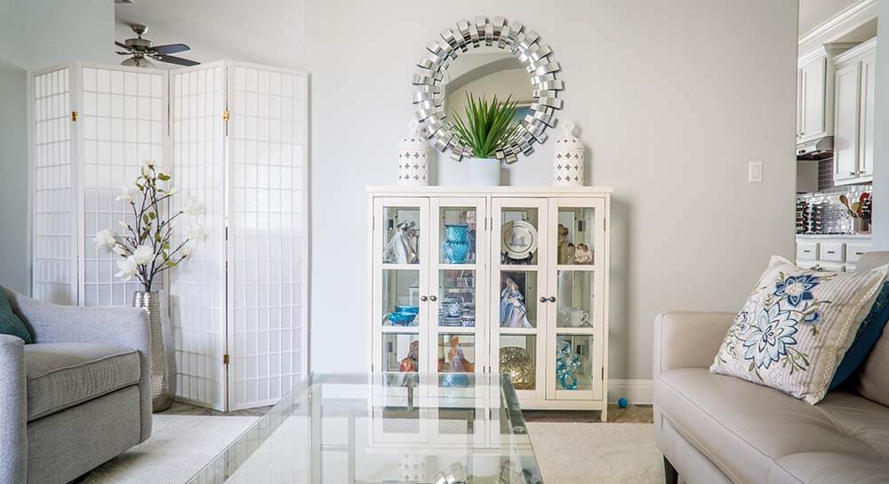 silver sunburst mirror on a wall in a contemporary white living room